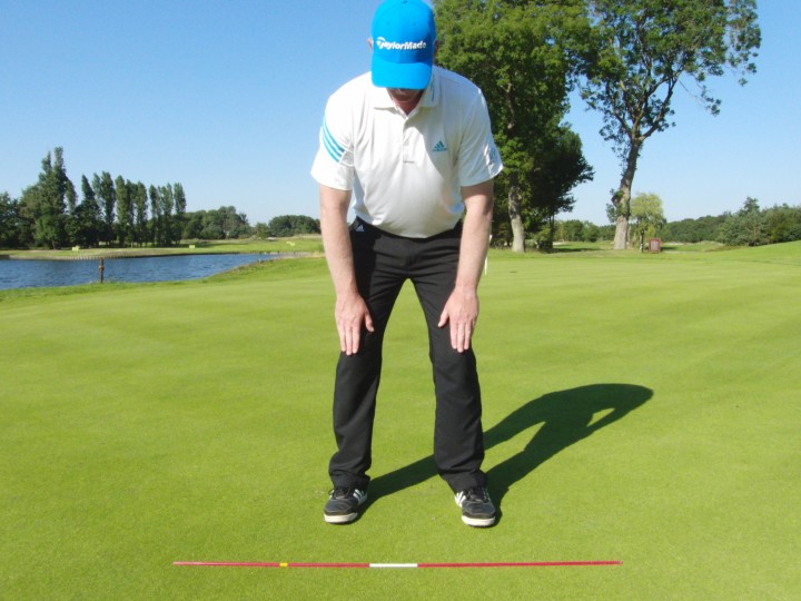 Voor de correcte putt houding, buig vanuit je heupen naar voren en je knieën aanraken met je vingertoppen.
